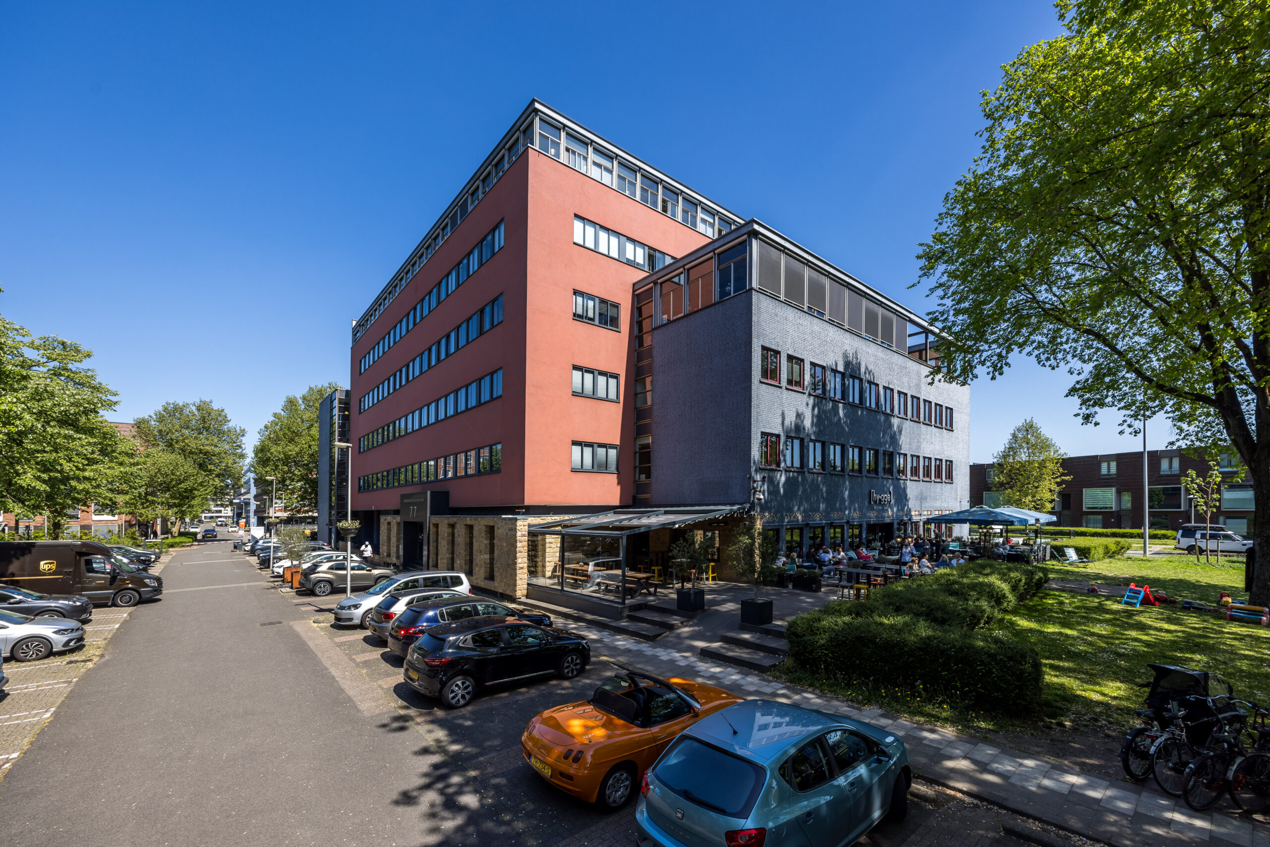 Kantoorgebouw met geparkeerde auto's en een terras aan de Goeman Borgesiuslaan 77 in Utrecht.