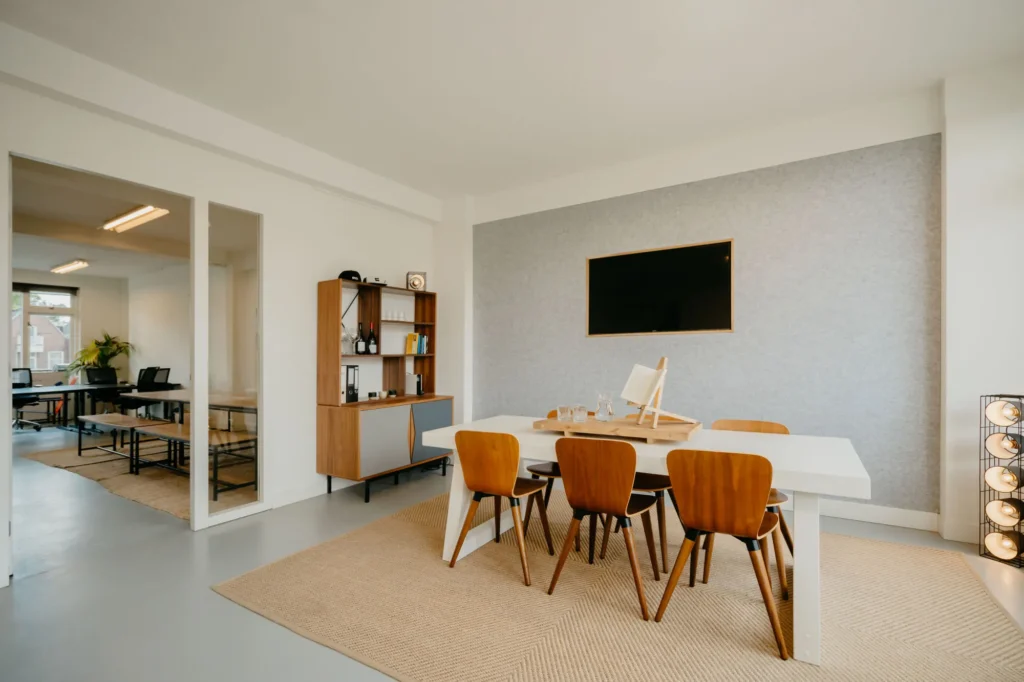 Moderne vergaderruimte met houten meubels, een grote tafel en een flatscreen aan de muur.