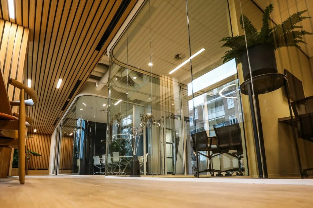 Moderne kantoorruimte met glazen wanden, houten plafond en vergaderruimtes met designmeubilair.
