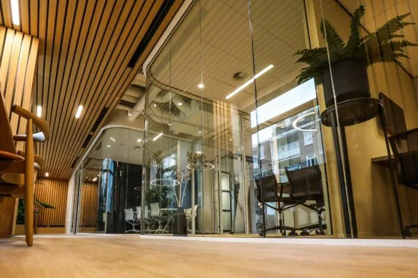 Moderne kantoorruimte met glazen wanden, houten plafond en vergaderruimtes met designmeubilair.