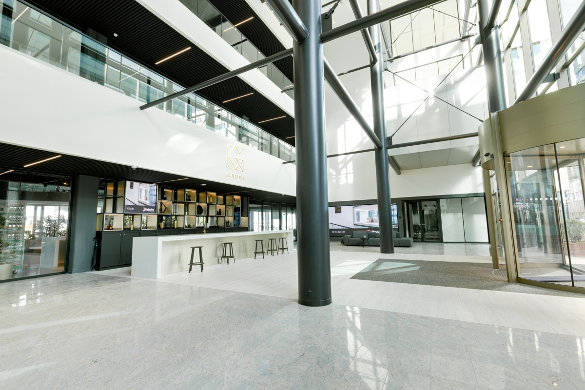 Moderne lobby van het Gaudi-gebouw met hoge plafonds en een centraal ingerichte balie.