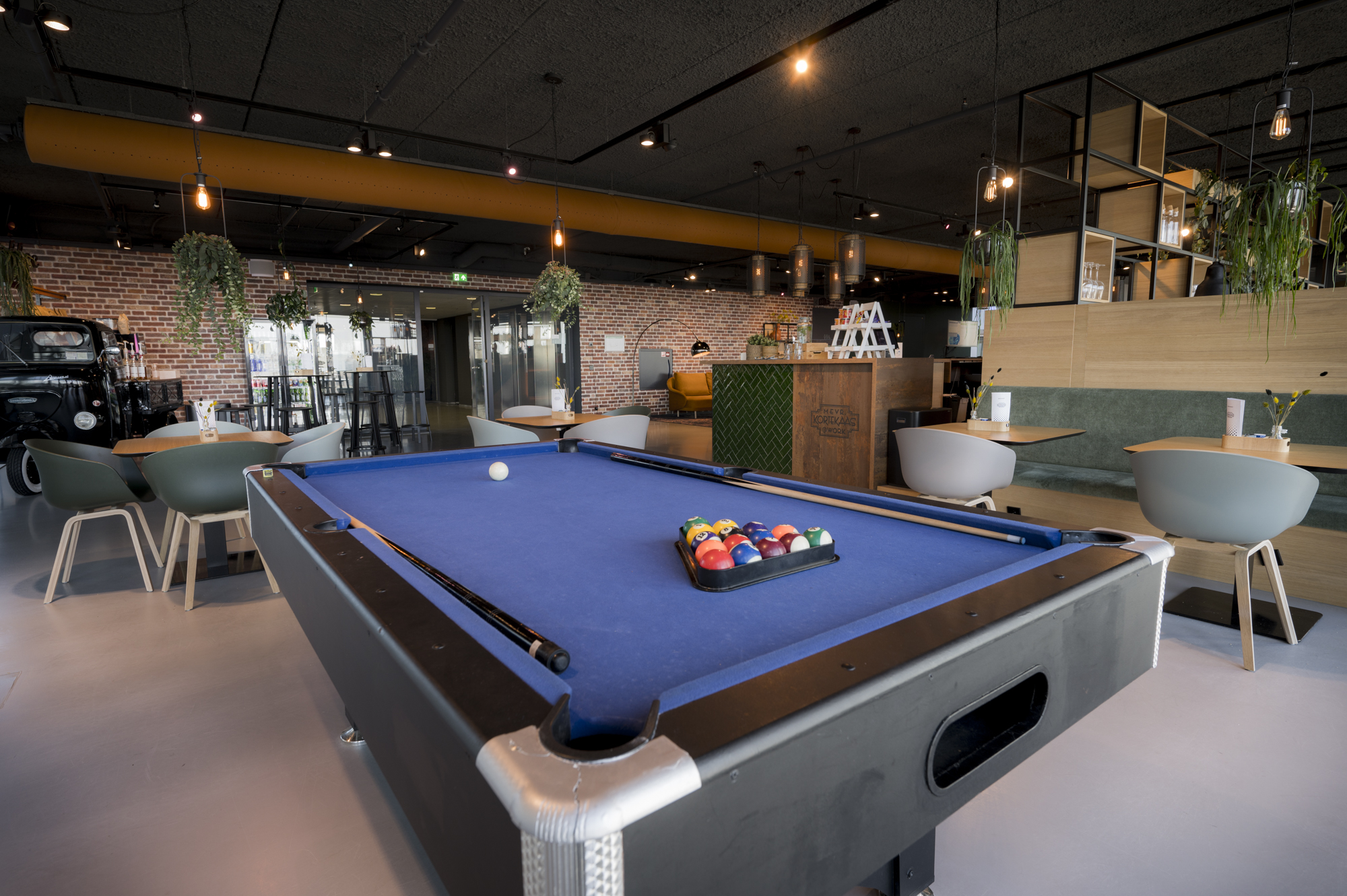 Een sfeervolle clubruimte met een pooltafel en moderne zitplaatsen.