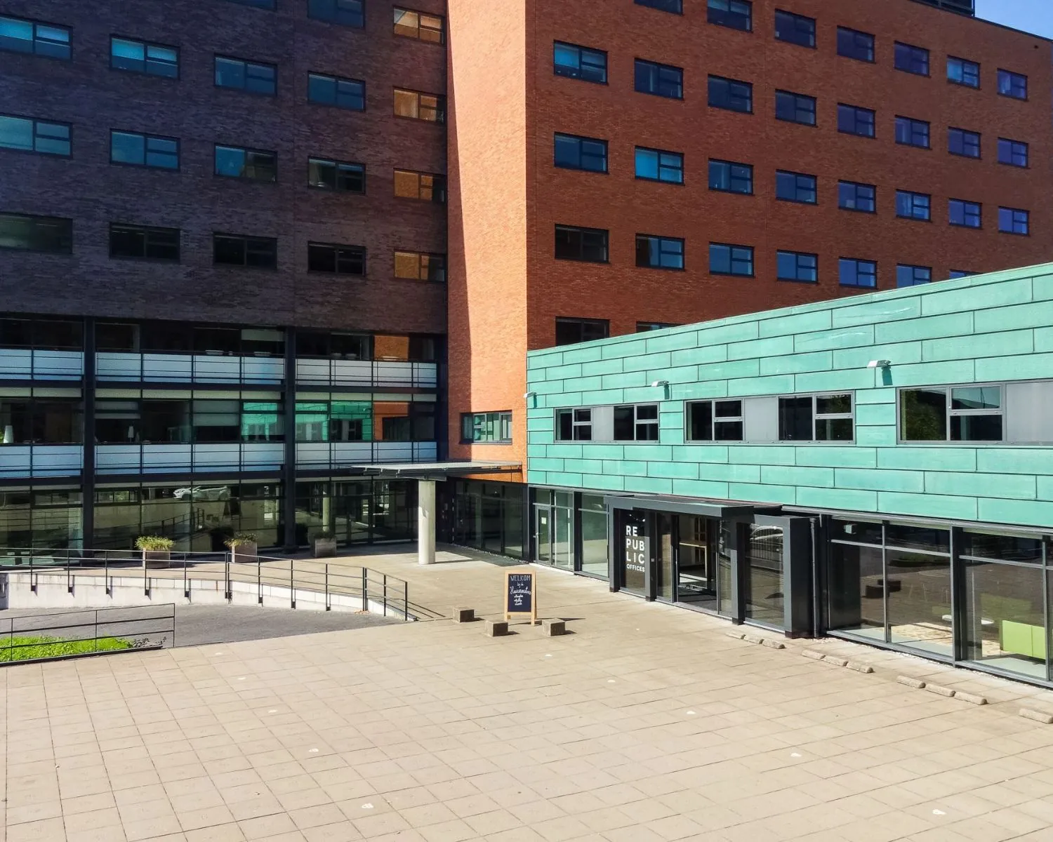 Binnenplein met moderne kantoorgebouwen, waaronder het Republic Offices-pand, onder een heldere blauwe lucht.