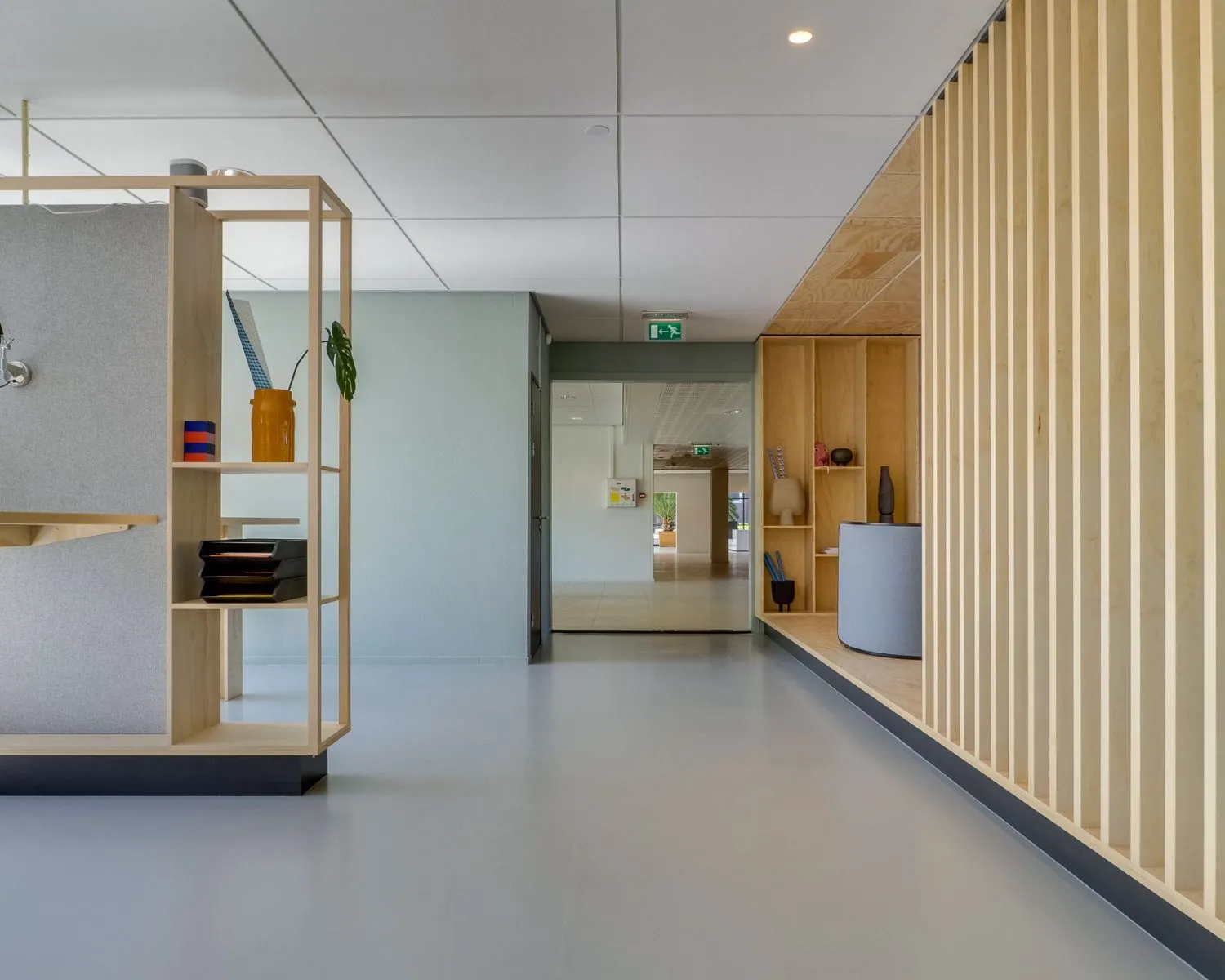 Moderne en minimalistische kantoorruimte met houten elementen, open planken en strakke afwerking.