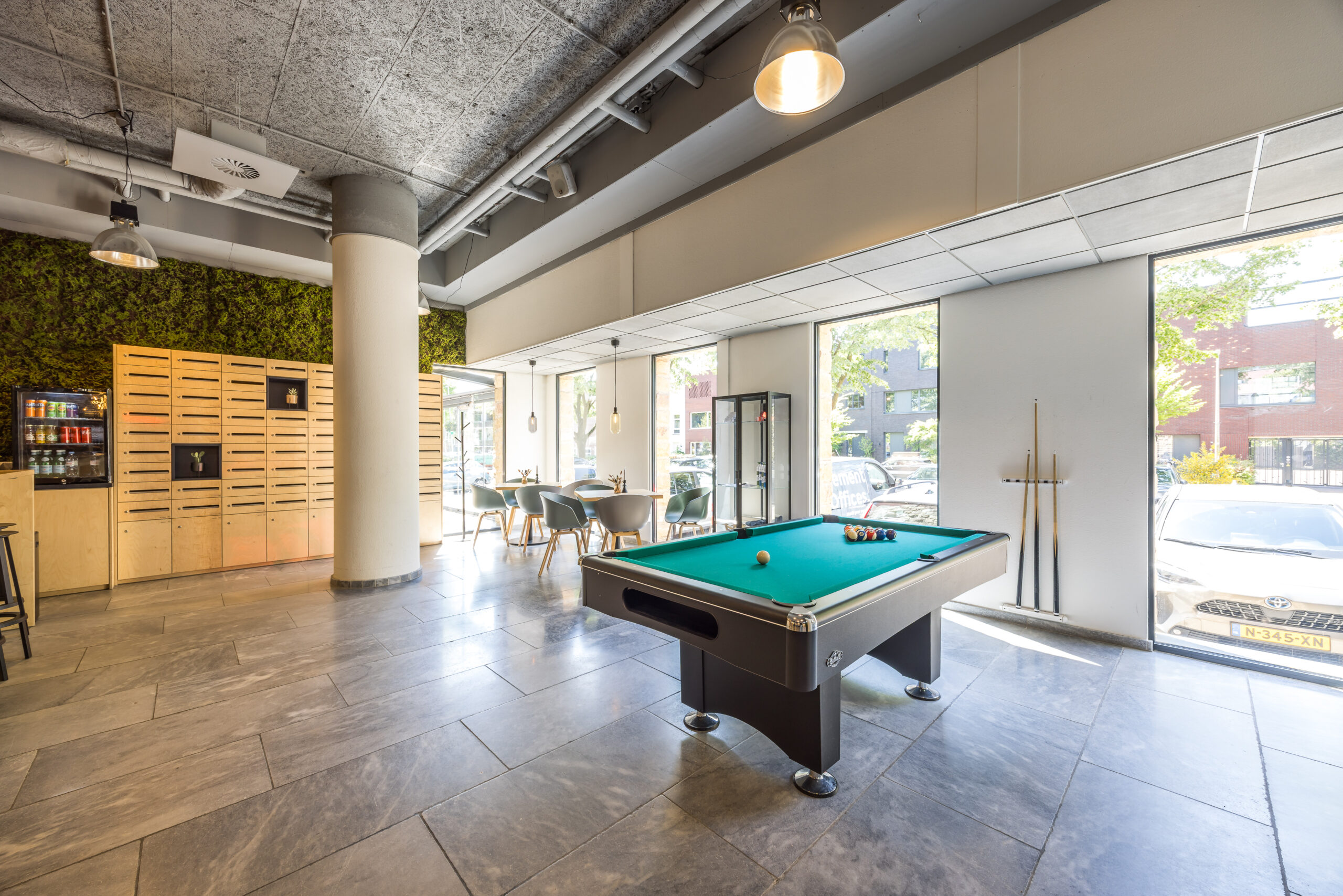 Modern kantoorentree met biljarttafel, zitgedeelte en groene muur bij Element Offices in Utrecht.