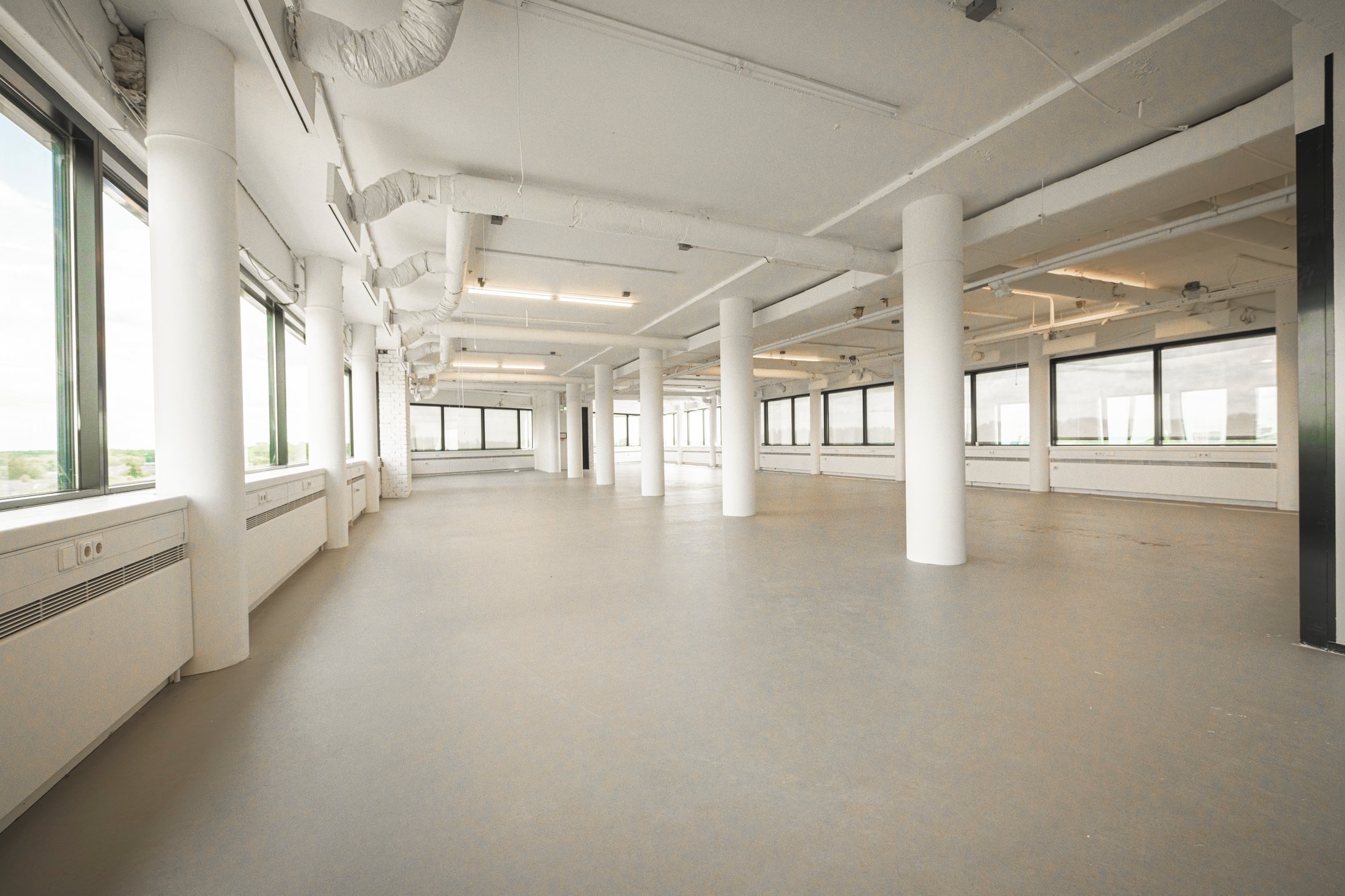 Leeg, industrieel ogend kantoor met grote ramen en witte steunpilaren in gebouw 086_2160.
