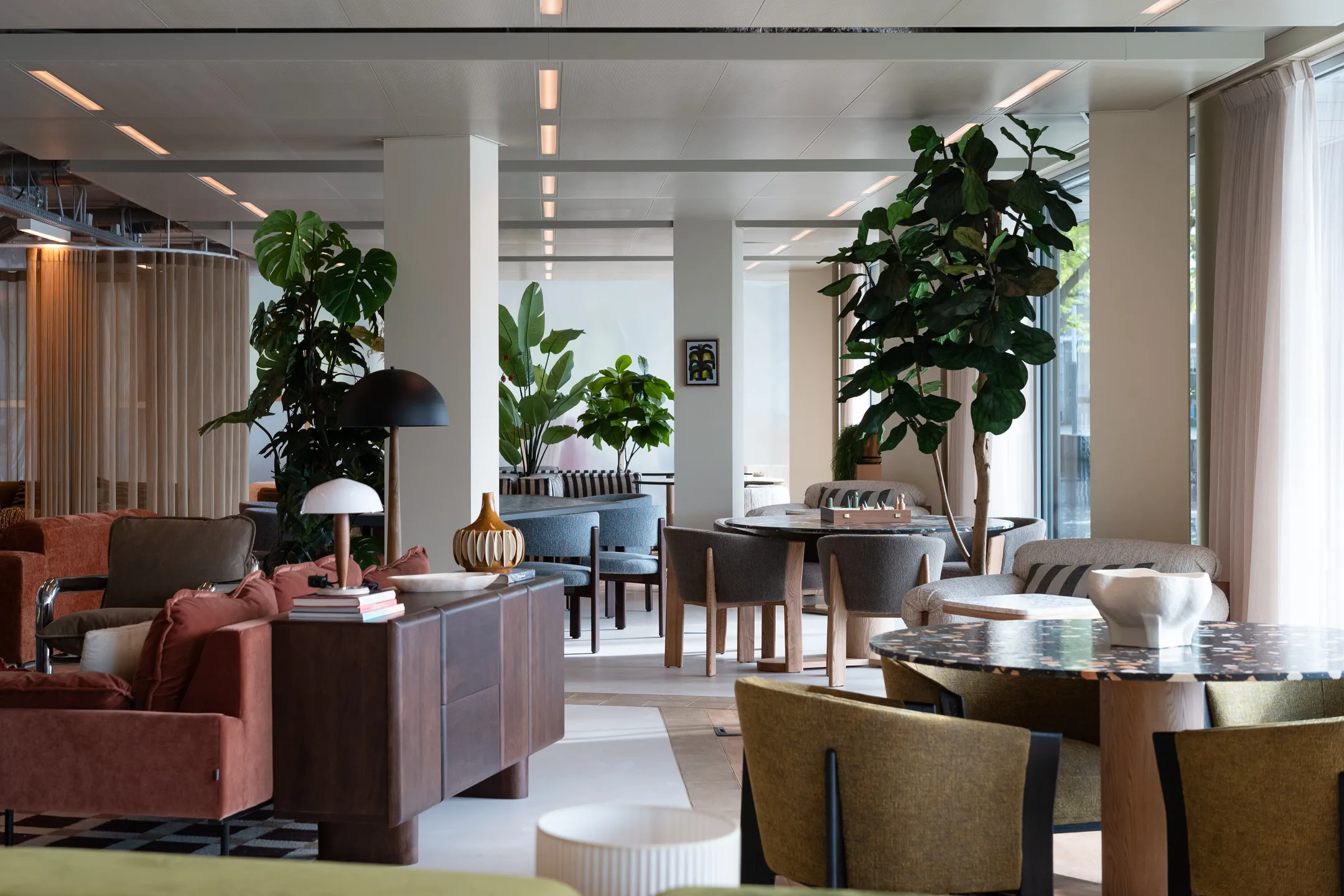 Een stijlvolle, moderne woonkamer met meubels, kamerplanten en kunst aan de muur.