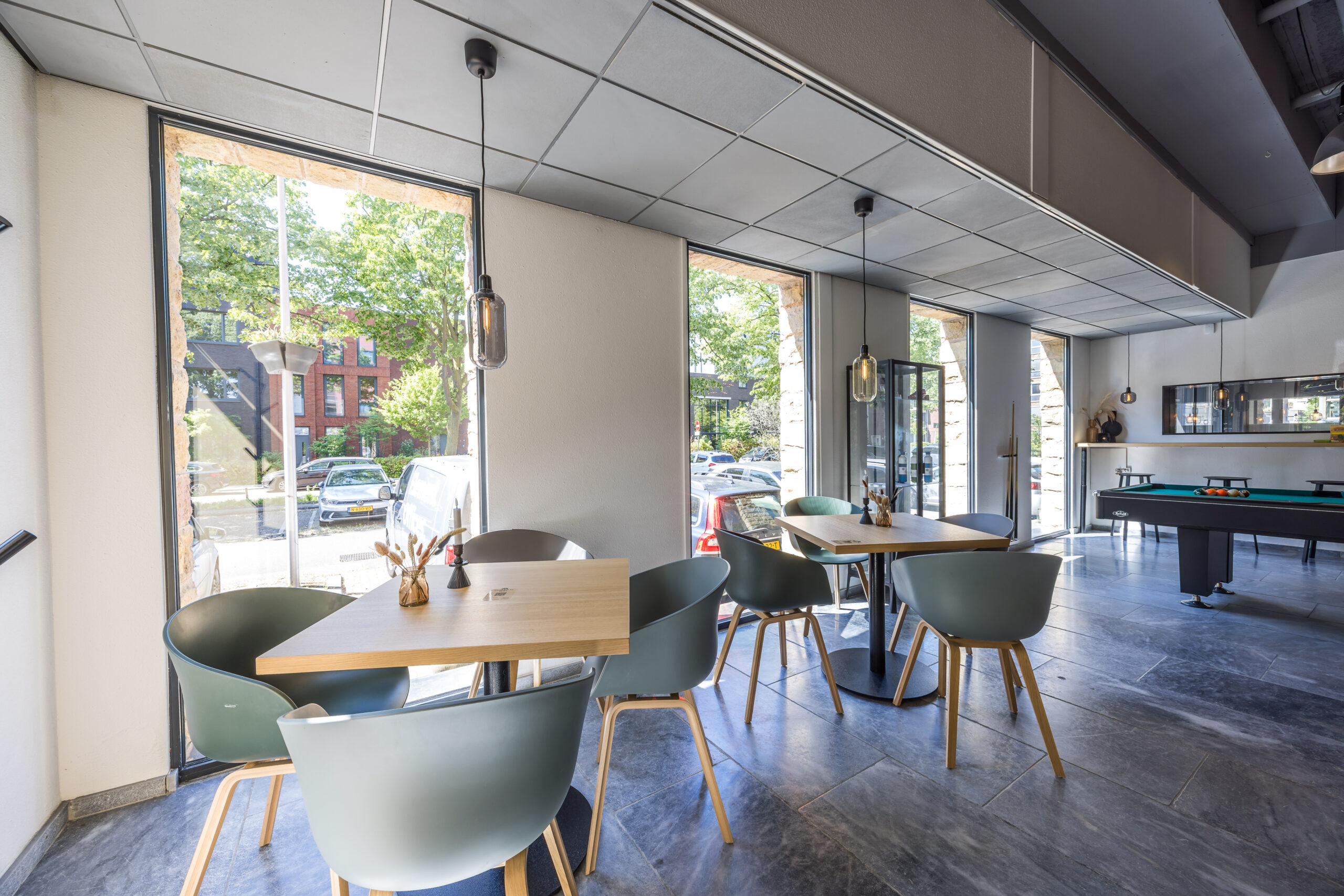 Een moderne kantoorruimte met tafels en stoelen naast grote ramen bij Element Offices aan de Goeman Borgesiuslaan 77 in Utrecht.