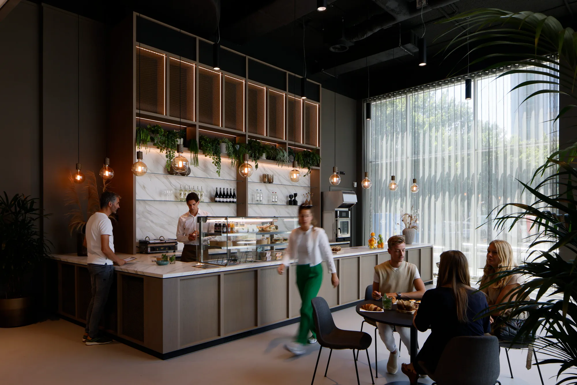 Een moderne koffiebar met mensen die aan de bar en tafels zitten in een lichte, sfeervolle ruimte.