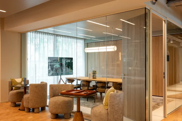 Een moderne vergaderruimte met glazen wanden, ingericht met comfortabele stoelen en een tv-scherm.