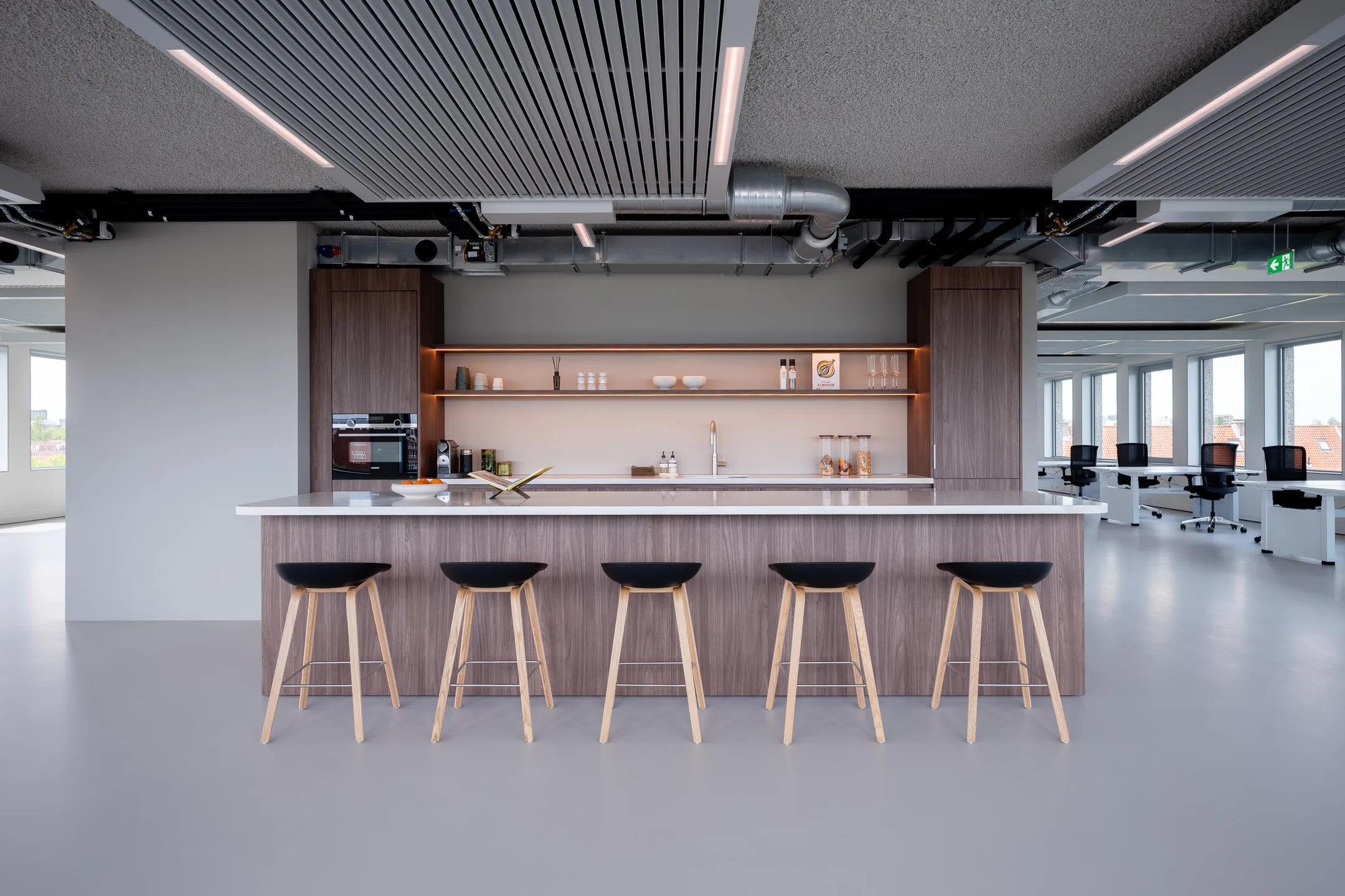 Een moderne kantoorruimte met een stijlvolle keuken en zithoek met barkrukken.