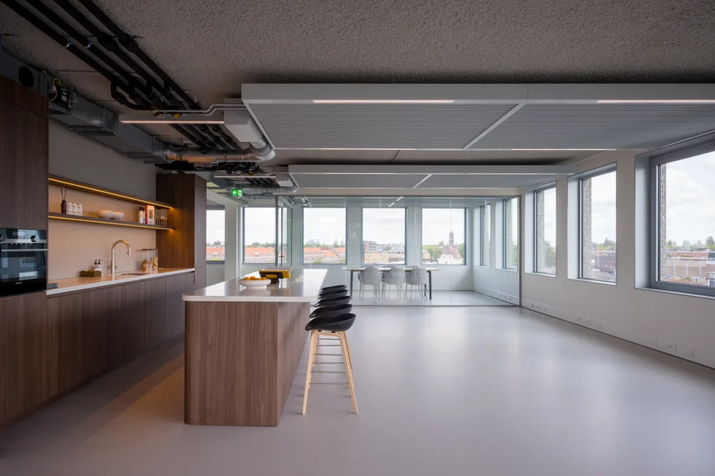 Een moderne keuken en eetruimte met veel ramen en uitzicht op de stad.