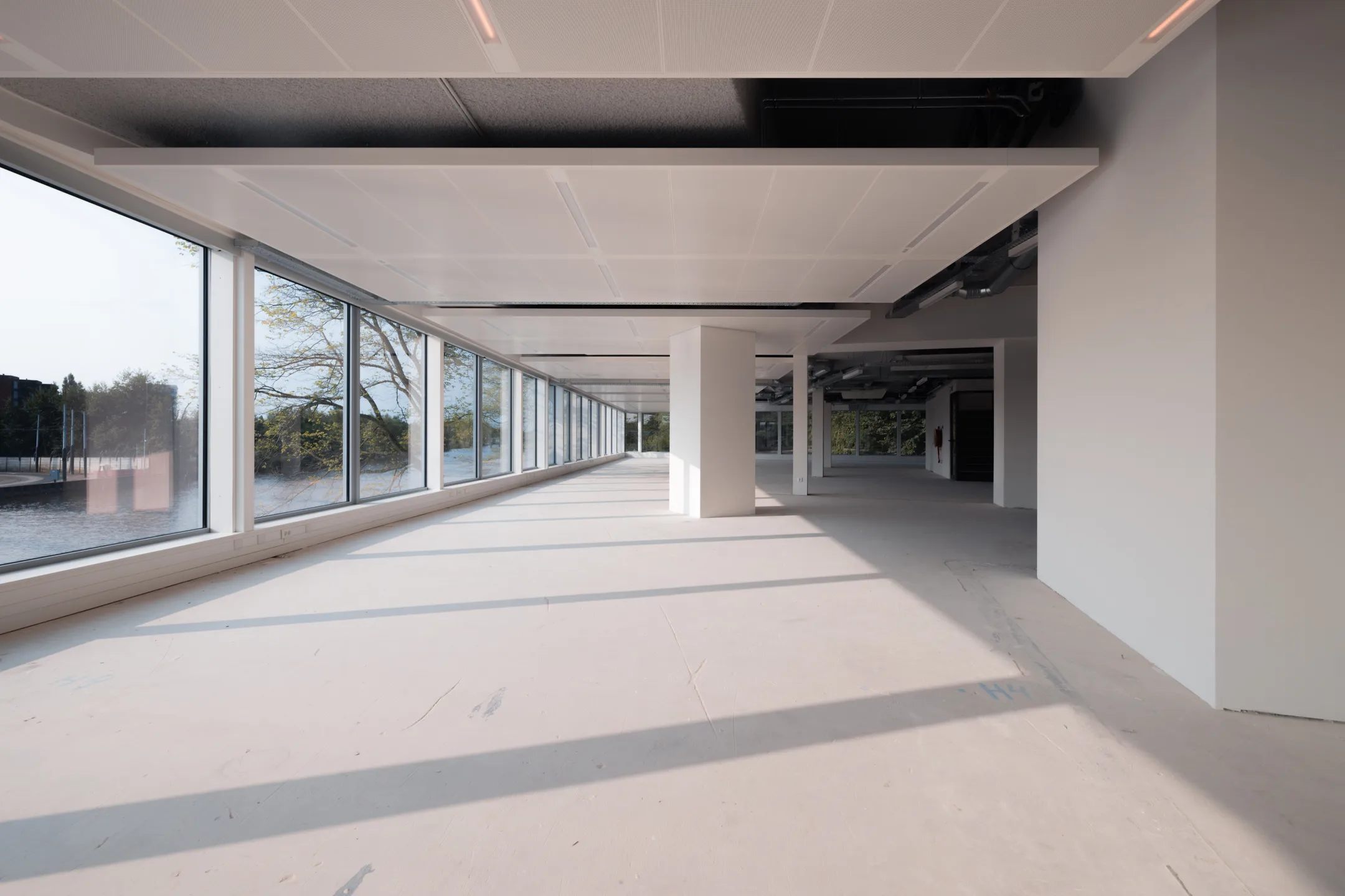 Lichtovergoten, lege kantoorruimte met grote ramen en uitzicht op buiten.