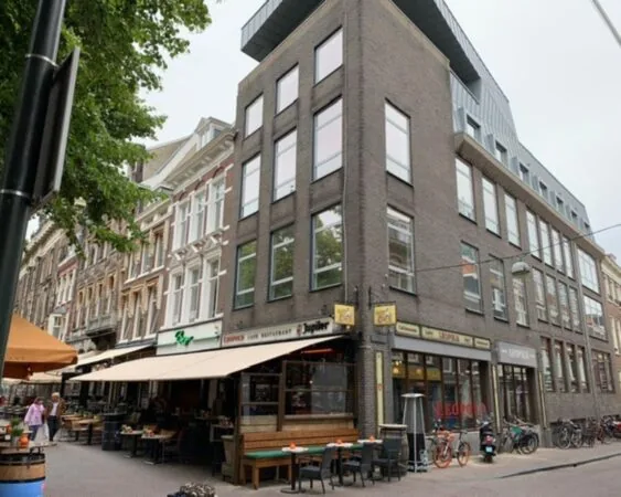 Hoekpand in een stadsstraat met café-restaurant Leopold en diverse terrassen.