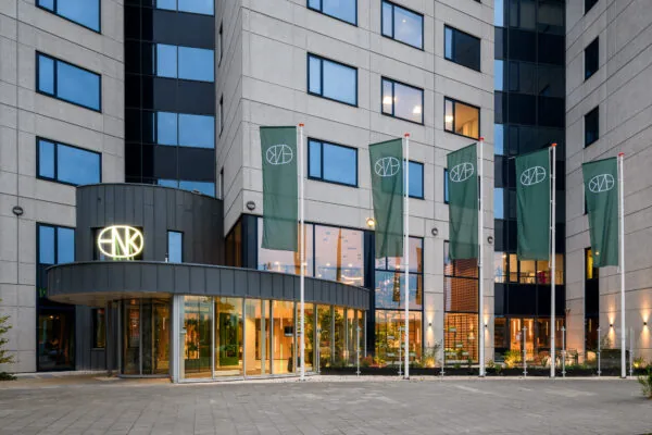 Voorgevel van HNK Amsterdam Sloterdijk met groene vlaggen en verlichte entree.