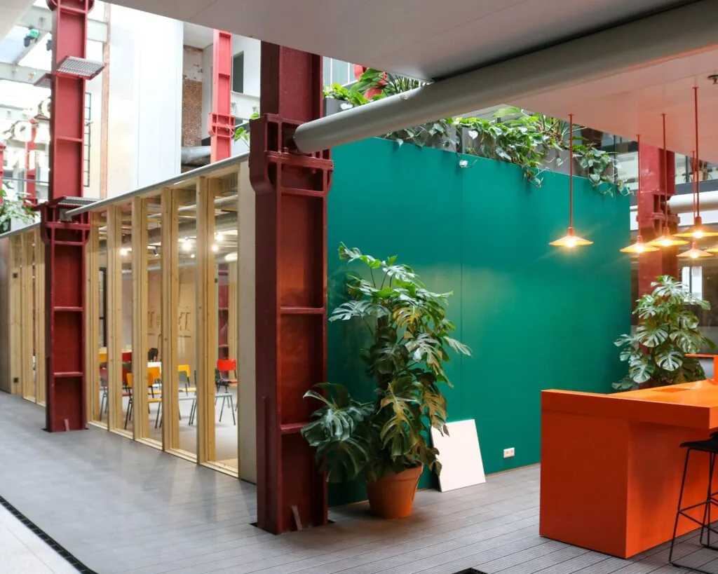 Moderne kantoorruimte in Vijf Werelddelen 69 in Rotterdam met veel planten, kleurrijke meubels en industriële accenten.