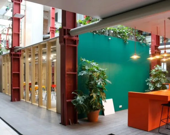 Moderne kantoorruimte in Vijf Werelddelen 69 in Rotterdam met veel planten, kleurrijke meubels en industriële accenten.