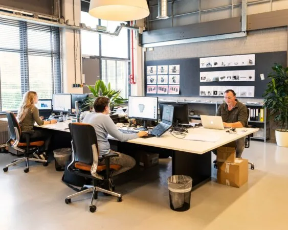 Drie mensen werken op computers in een moderne kantoorruimte aan de Bolderweg 2 in Almere.