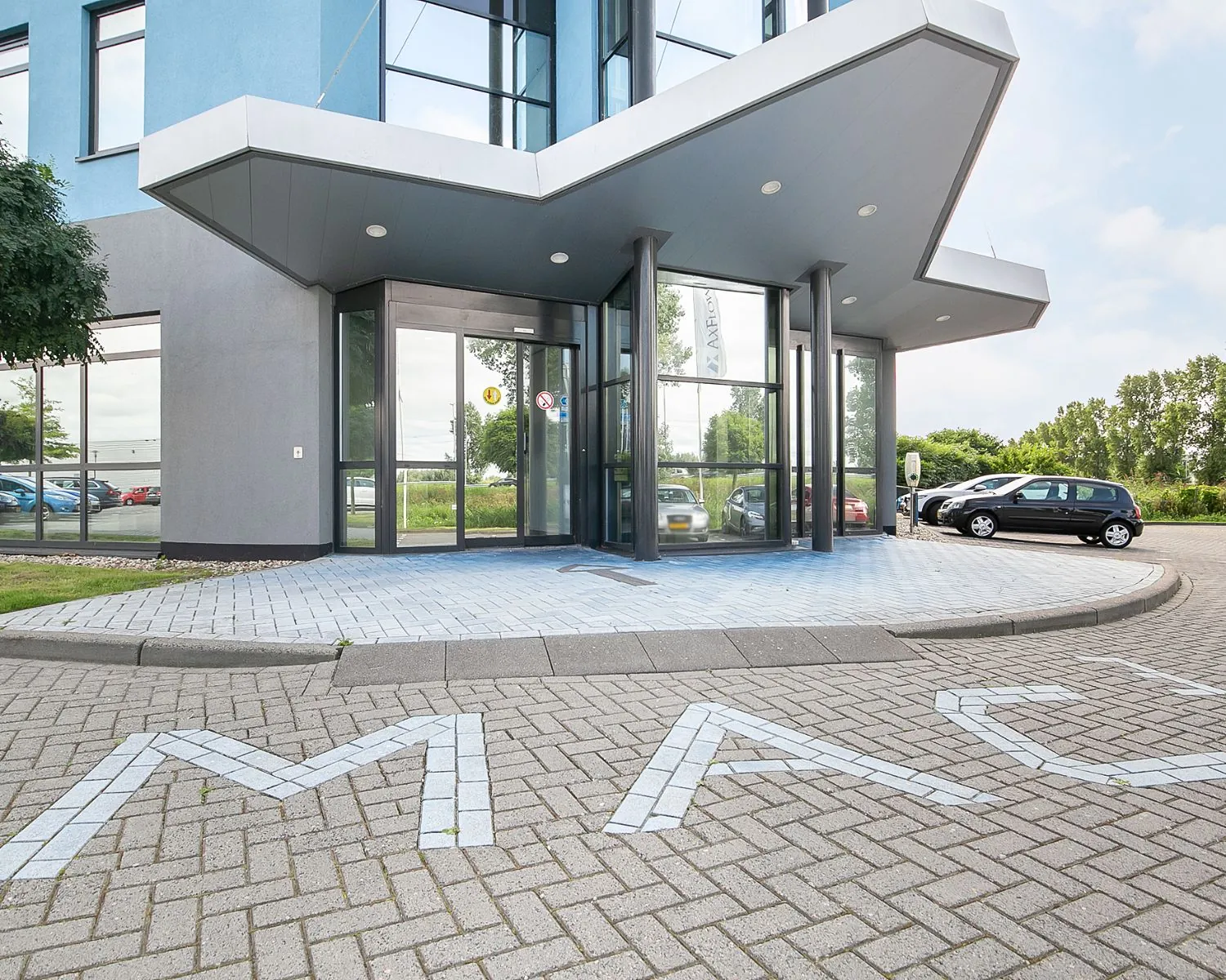 Ingang van een modern kantoorgebouw aan de Pascallaan 60-78 in Lelystad met parkeerplaatsen voor de deur.