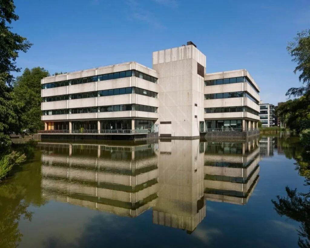 Modern kantoorgebouw aan de Prof. E.M. Meijerslaan 3 in Amstelveen, weerspiegeld in een omliggende vijver.