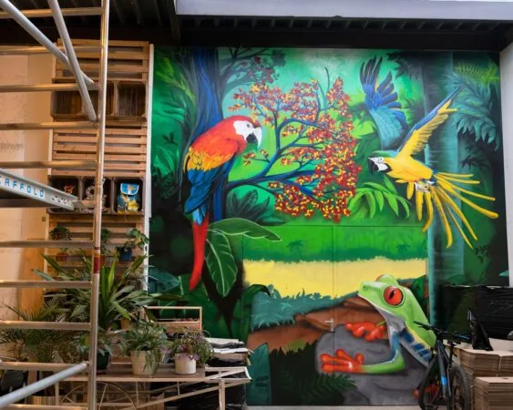 Muurschildering in kantoorruimte aan de Steiger 24 in Almere met kleurrijke tropische dieren zoals papegaaien en een boomkikker.