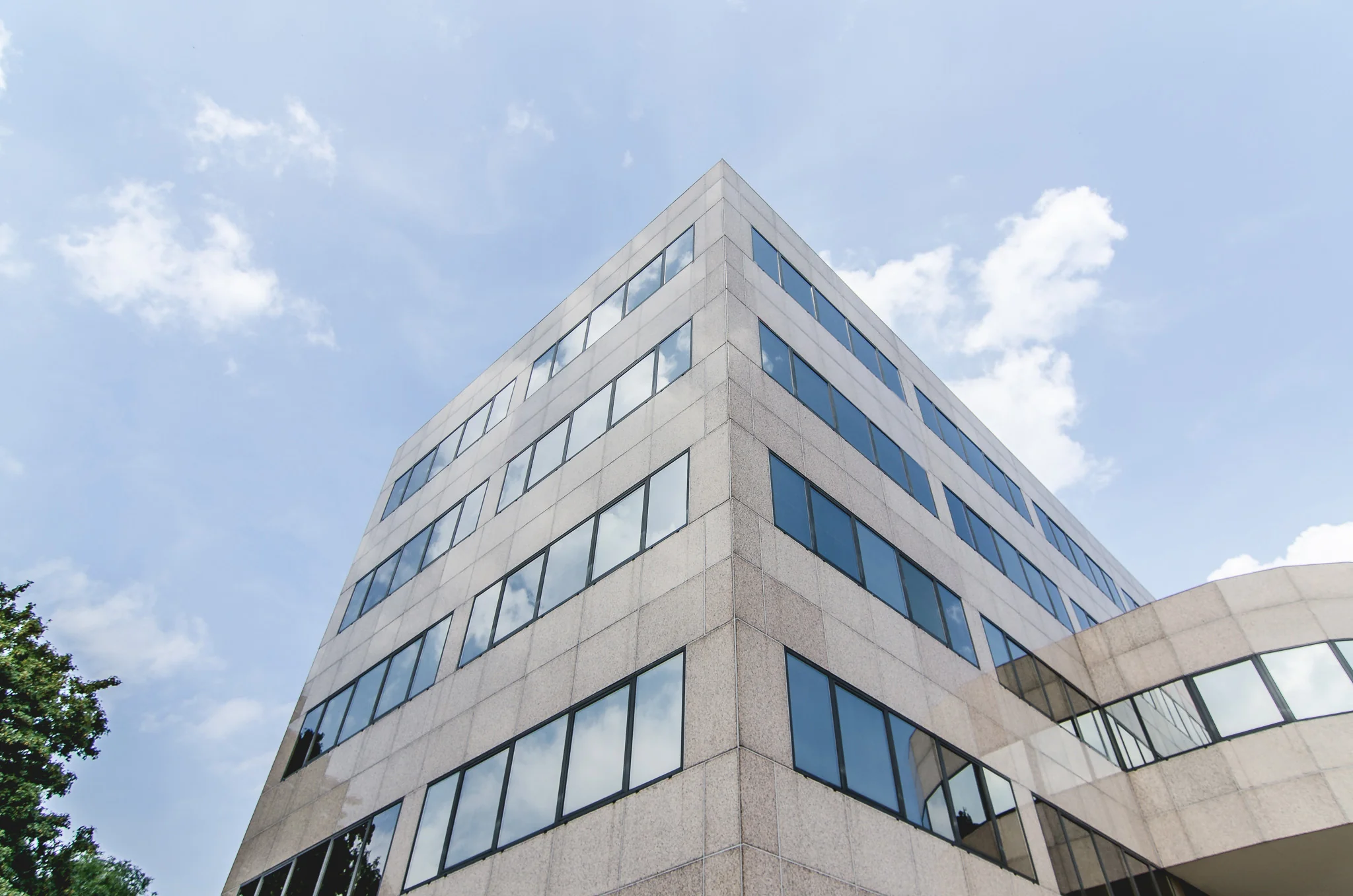 Hoekaanzicht van het moderne kantoorgebouw HNK Utrecht West onder een blauwe lucht.