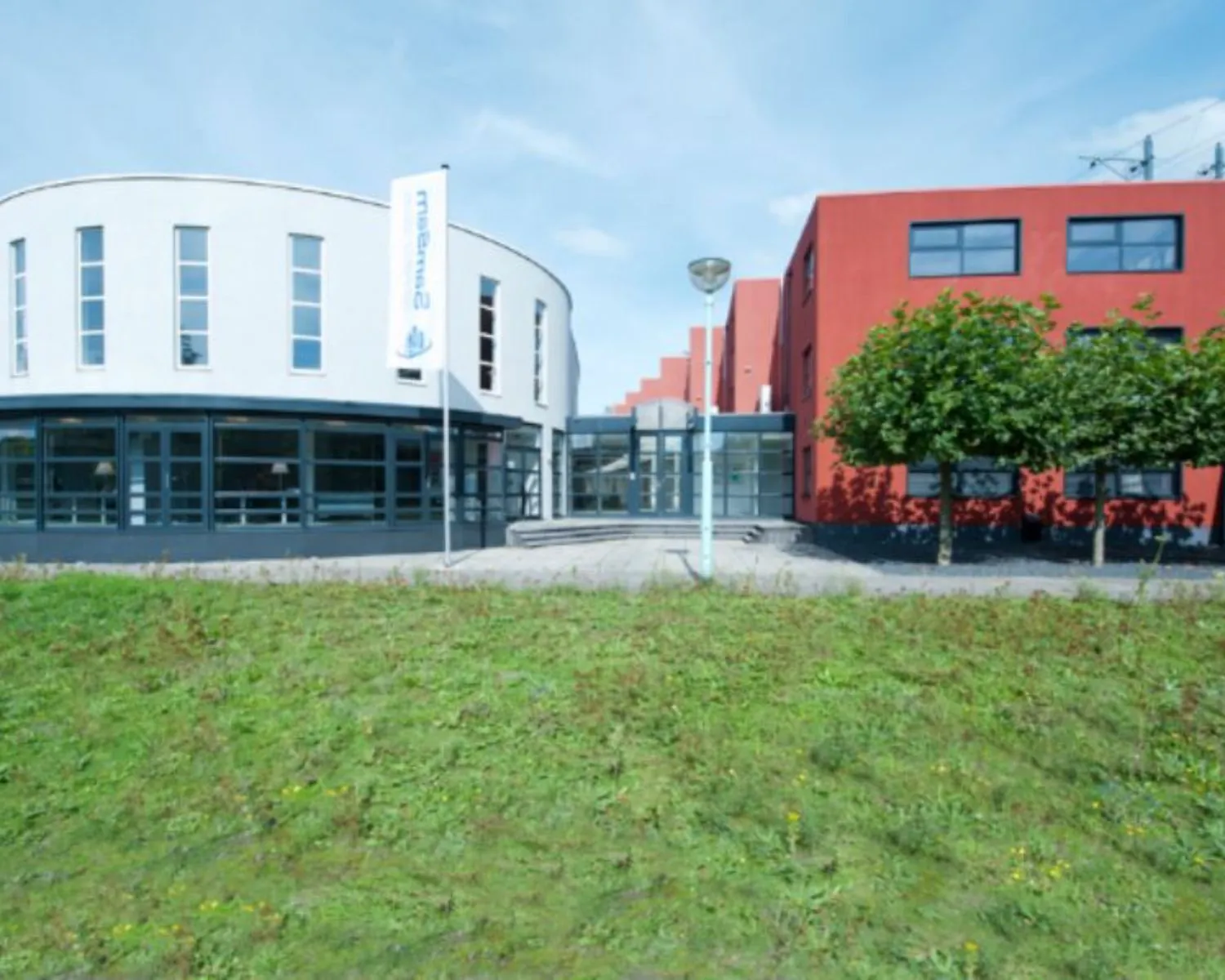 Moderne kantoorruimte aan de Arlandaweg 92 in Amsterdam met een wit en rood gebouw en groene voortuin.