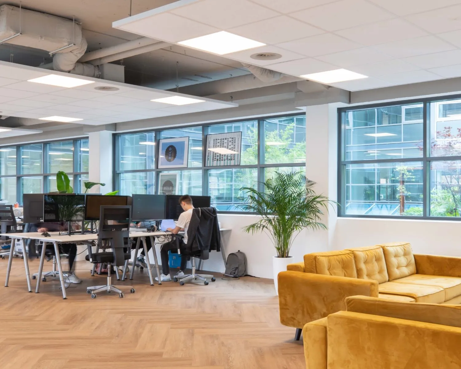 Moderne kantoorruimte in het Coengebouw aan de Kabelweg 37 in Amsterdam met werkplekken, gele loungehoek en grote ramen.