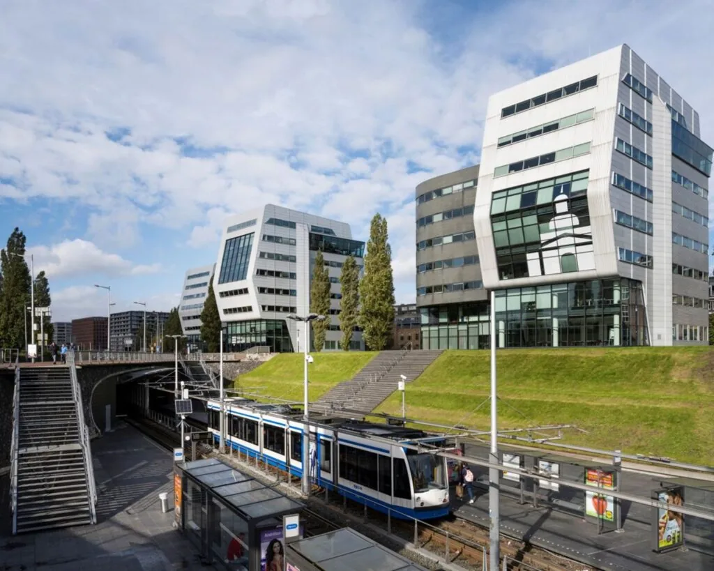 Modern kantoorgebouw aan het Rietlandpark 301 in Amsterdam met een tramhalte op de voorgrond.