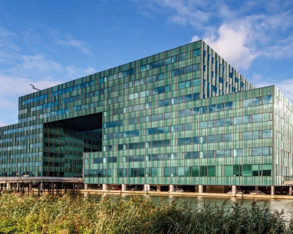 Moderne kantoorgebouw Herikerbergweg 292 in Amsterdam met groene glazen gevel aan het water.