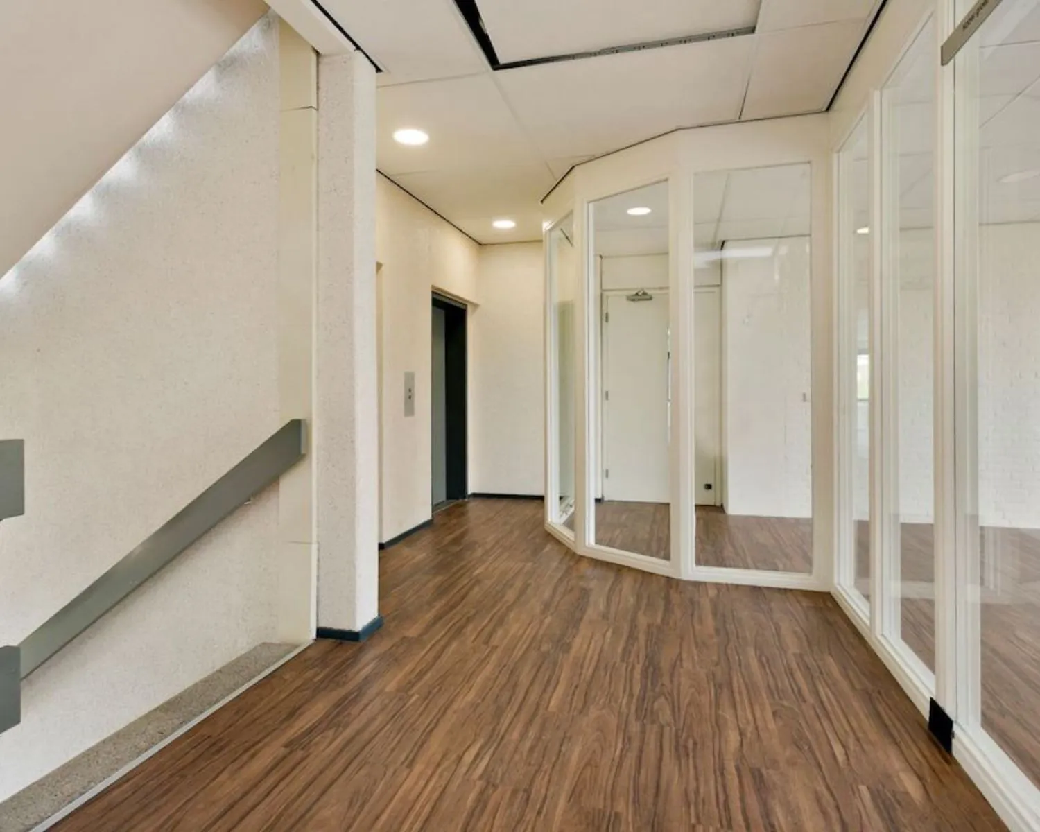Moderne kantoorruimte met houten vloer, glazen scheidingswanden en een lift aan de Hooilaan 1 in Breda.