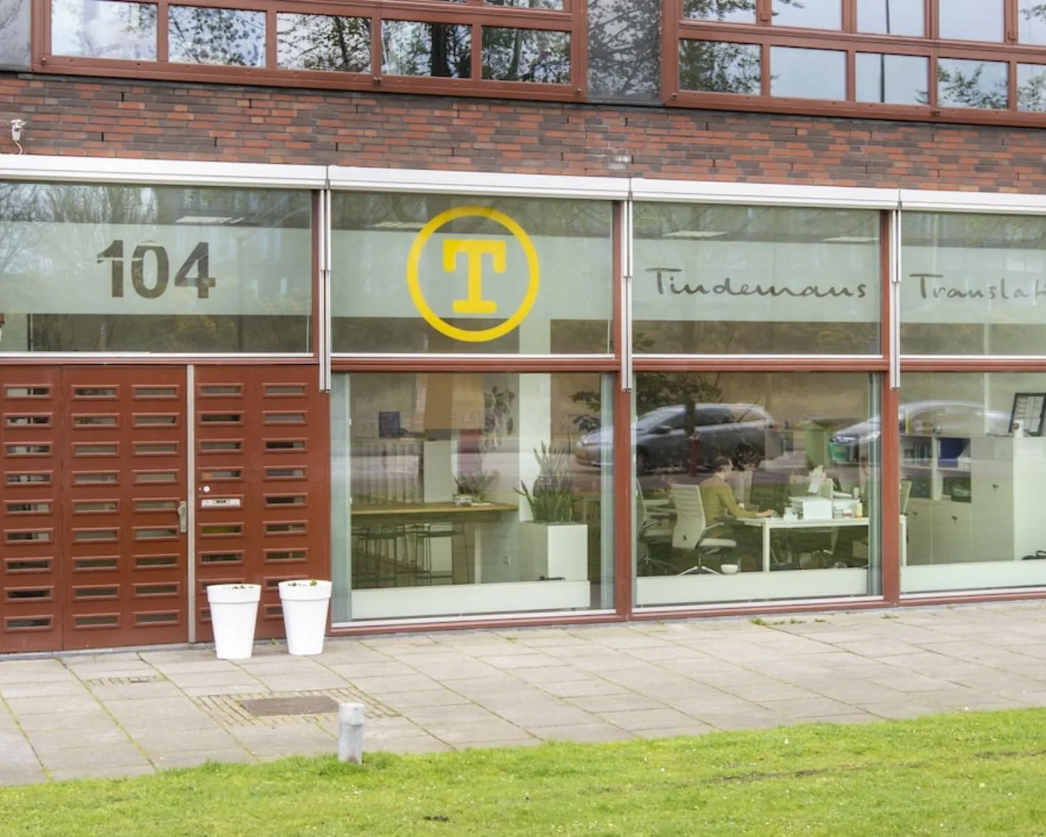 Vooraanzicht van kantoorruimte op Panamalaan 104 in Amsterdam met grote ramen en zicht op werkplekken binnen.