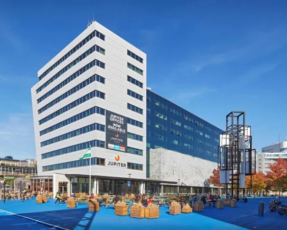Modern kantoorgebouw Jupiter aan het Prins Alexanderplein 5-21 in Rotterdam met terras en zitgelegenheden op een blauw plein.