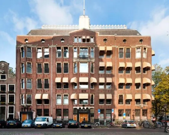 Vooraanzicht van een karakteristiek kantoorpand aan de Westermarkt 2 in Amsterdam met markante zonweringen en geparkeerde auto's ervoor.