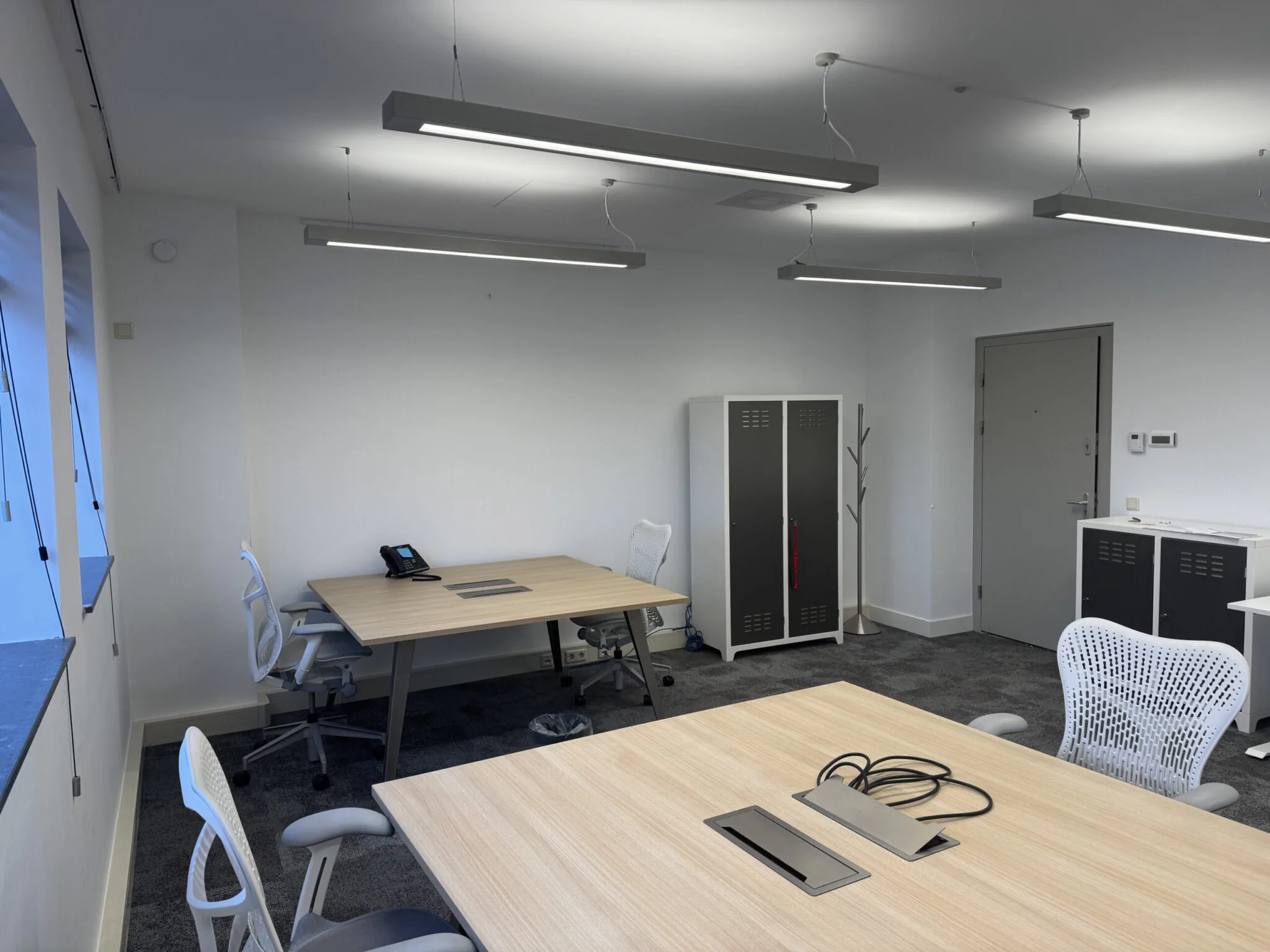 Modern ingerichte kantoorruimte 1.01B met bureaus, ergonomische stoelen, een telefoon en opbergkasten.