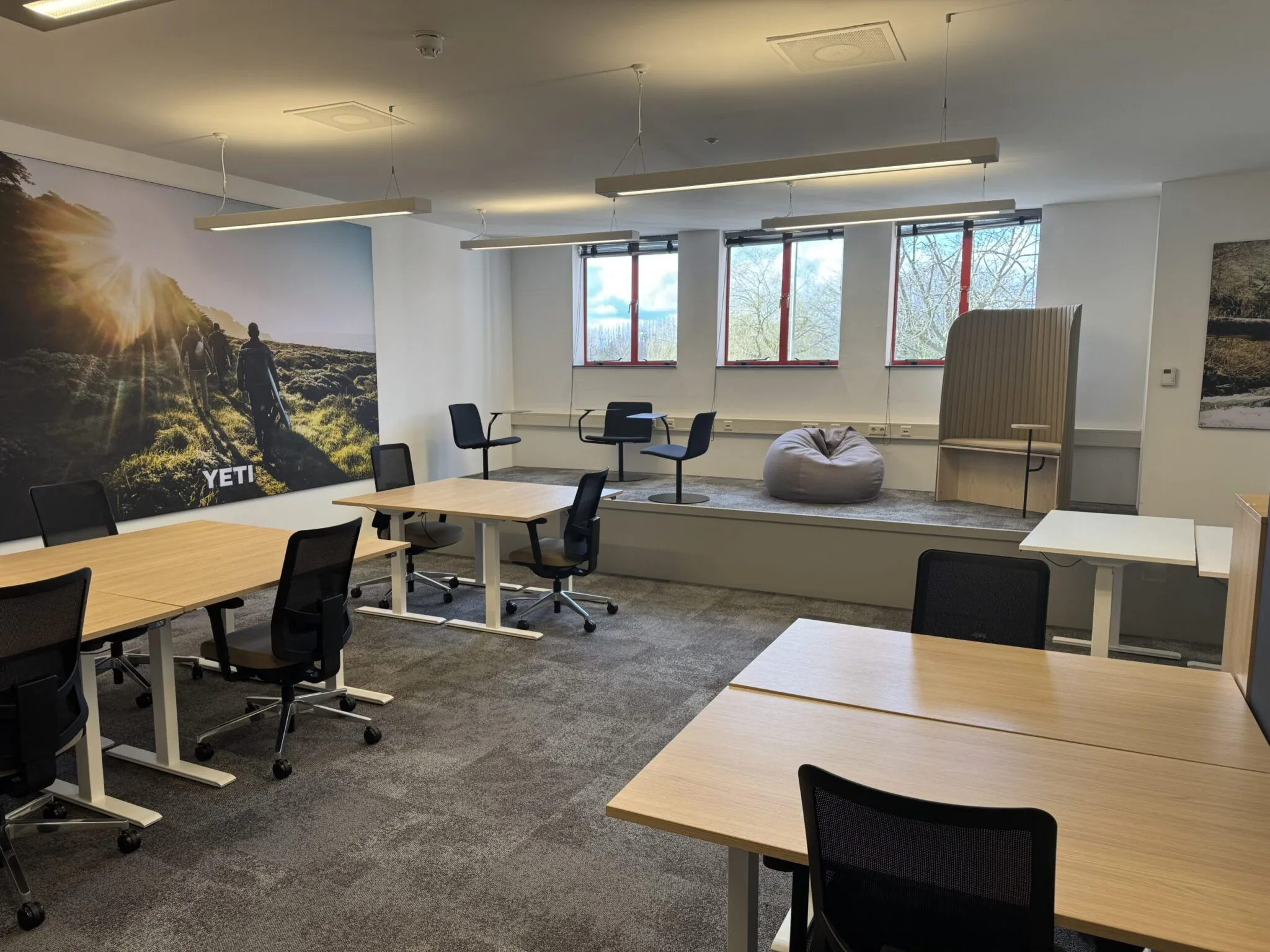 Modern kantoor met flexibele werkplekken, bureaustoelen, een zithoek en een grote wandfoto met het woord "YETI".