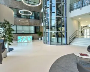 Moderne en lichte entreehal met een receptiebalie, glazen lift en stijlvolle verlichting.