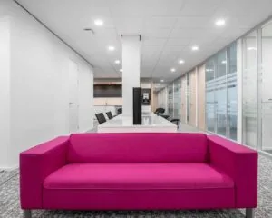 Moderne kantoorruimte aan de Hurksestraat 43 in Eindhoven met een opvallende fuchsia bank in de ontvangst- of wachtruimte.