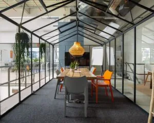 Vergaderruimte in kasconstructie met houten tafel, kleurrijke stoelen en hanglamp in kantoor aan de Bolderweg 2 in Almere.