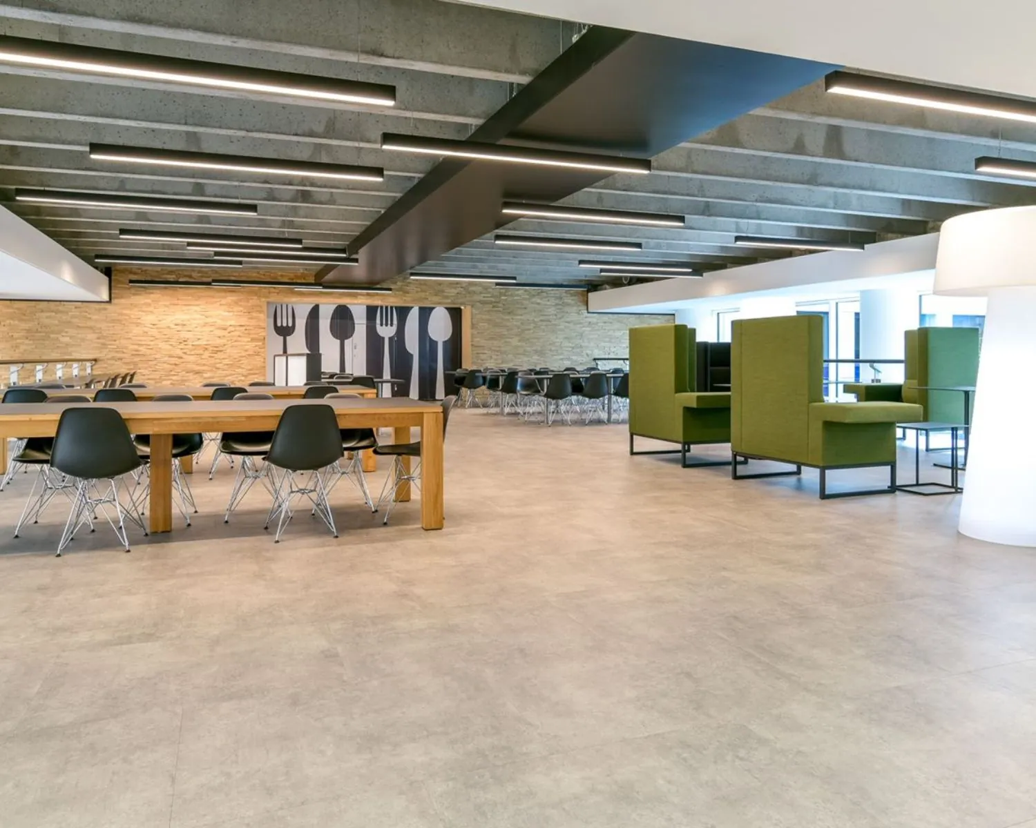 Moderne kantoorruimte in het Coengebouw aan de Kabelweg 37 in Amsterdam met open zitgedeelte, lange houten tafels en groene loungezitjes.