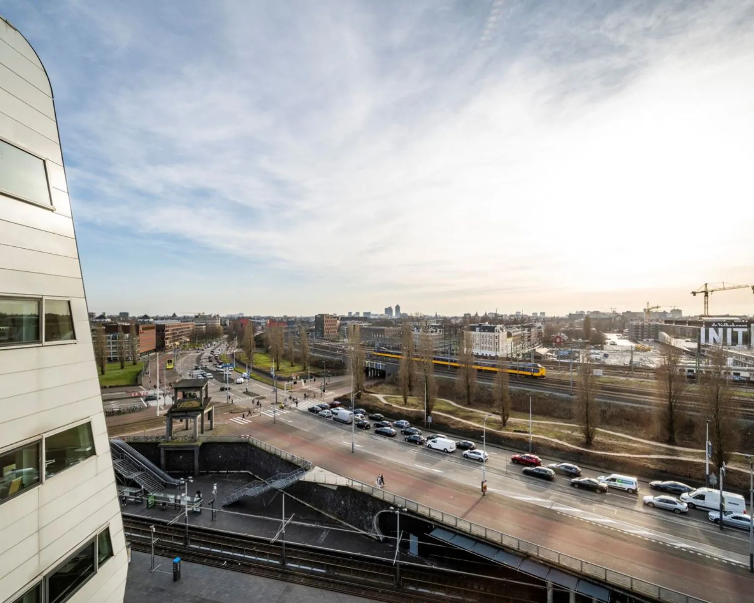Uitzicht vanaf kantoorruimte aan Rietlandpark 301 in Amsterdam met zicht op spoorlijn, wegen en omliggende gebouwen.