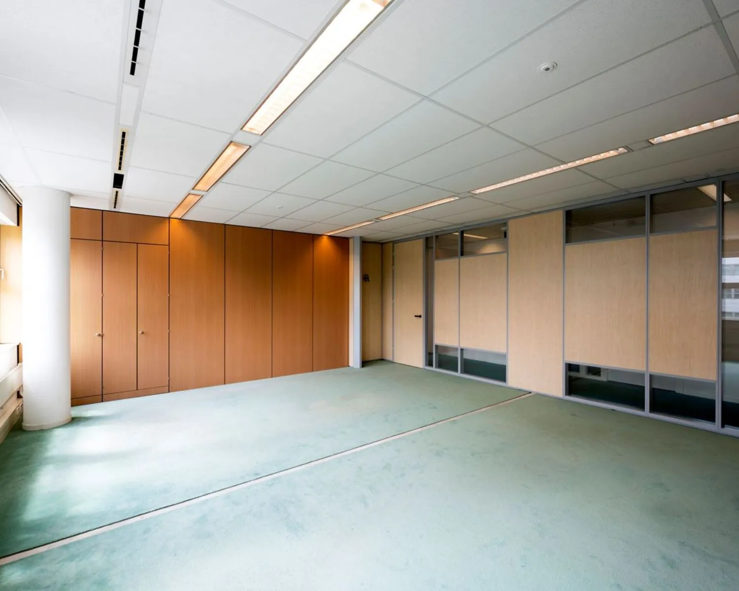 Lege kantoorruimte met houten wanden en glazen scheidingspanelen in Entrada 300 in Amsterdam.