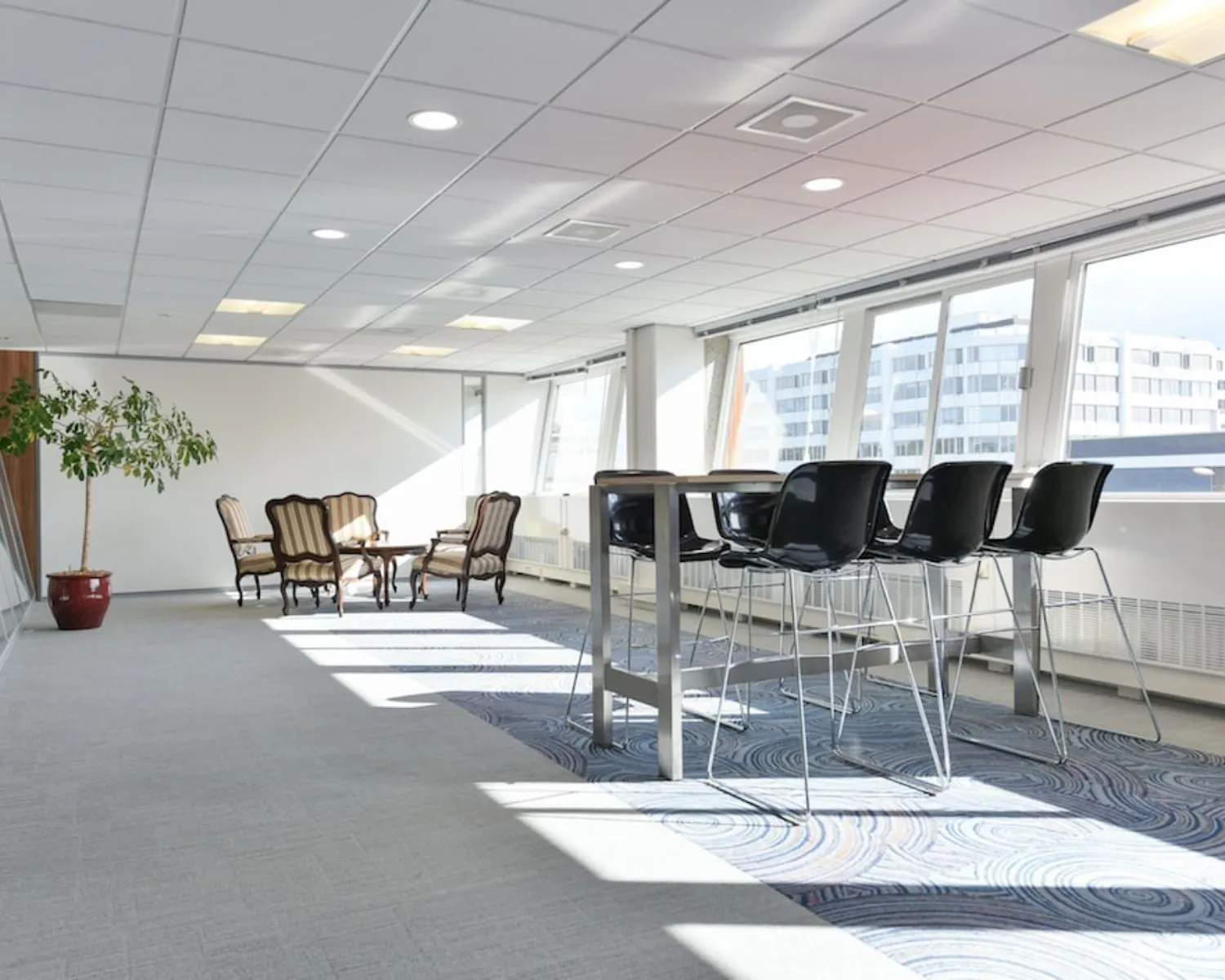 Moderne kantoorruimte aan de Treubstraat 1 in Rijswijk met zithoek, hoge tafels en veel natuurlijk licht.