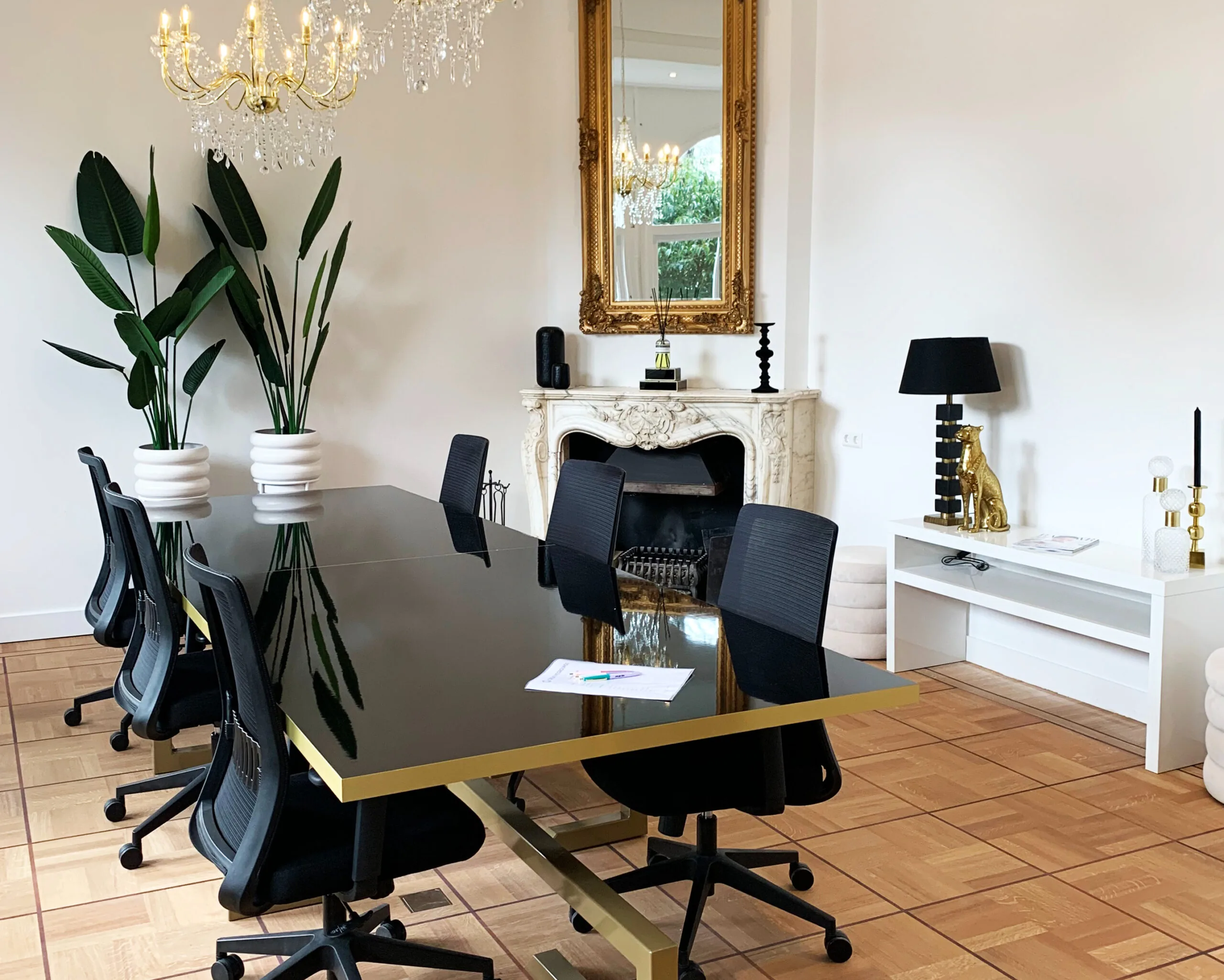 Luxe vergaderruimte bij Creativegrounds – Emmalaan met zwarte stoelen, glazen tafel, kroonluchters en een decoratieve schouw.