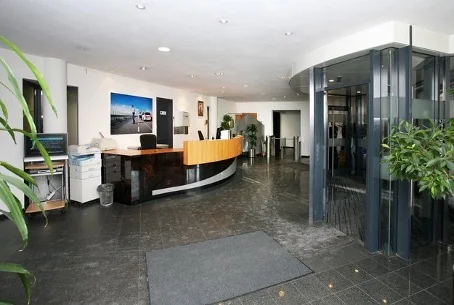 Moderne ontvangstruimte met receptiebalie, glazen draaideur en planten aan de Utrechtseweg.