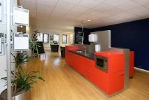 Moderne kantoorruimte met een rode kitchenette en houten vloer aan de Utrechtseweg.