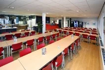 Moderne bedrijfskantine aan de Utrechtseweg met lange tafels en rode stoelen.