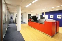 Moderne kantoorkeuken met feloranje keukeneiland aan de Utrechtseweg.