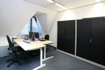 Kleine, moderne kantoorruimte aan de Utrechtseweg met twee bureaus, stoelen, computers en zwarte opbergkasten.