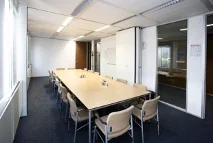 Vergaderruimte aan de Utrechtseweg met lange tafel, stoelen en een whiteboard.